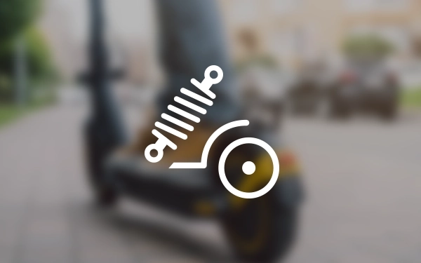 Значок заднього колеса скутера із символом амортизатора, що представляє задню підвіску, на тлі розмитого зображення поїздки