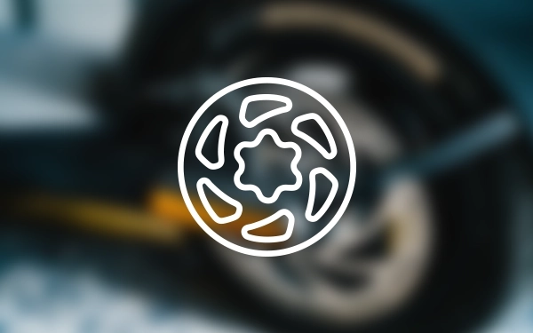 Значок колеса з візерунком диска та обода, що символізує суцільні шини скутера, на тлі розмитого зображення колеса