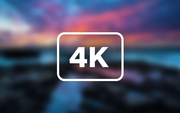 Значок зі словом 4K у рамці на розмитому фоні пейзажу із заходом сонця над морем.