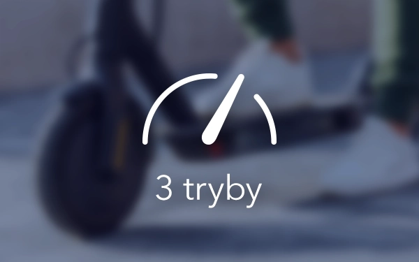 Значок спідометра з написом «3 режими» на розмитому фоні скутера та людини в білому взутті.