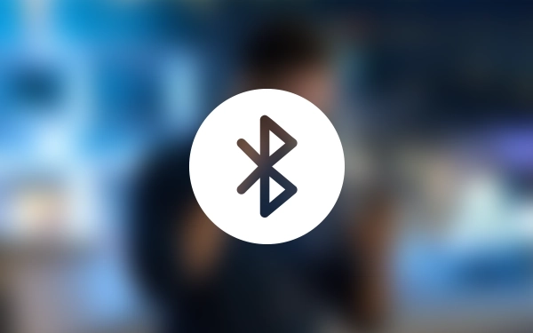 Білий логотип Bluetooth на розмитому синьо-сірому фоні.