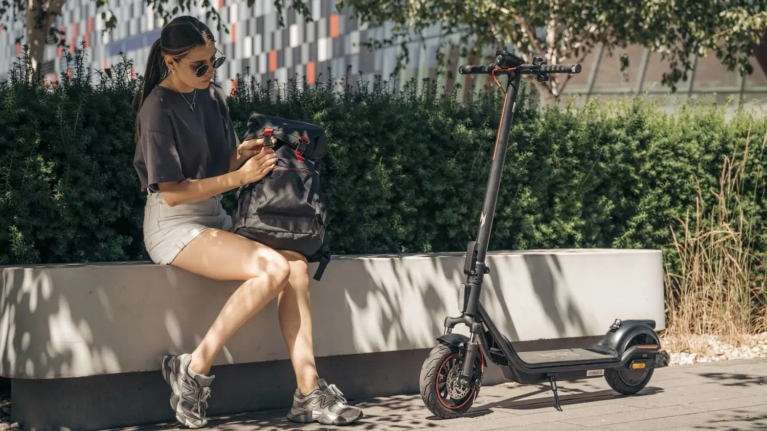 Жінка сидить зі скутером Acer Nitro; на задньому плані зелень та міські будівлі.