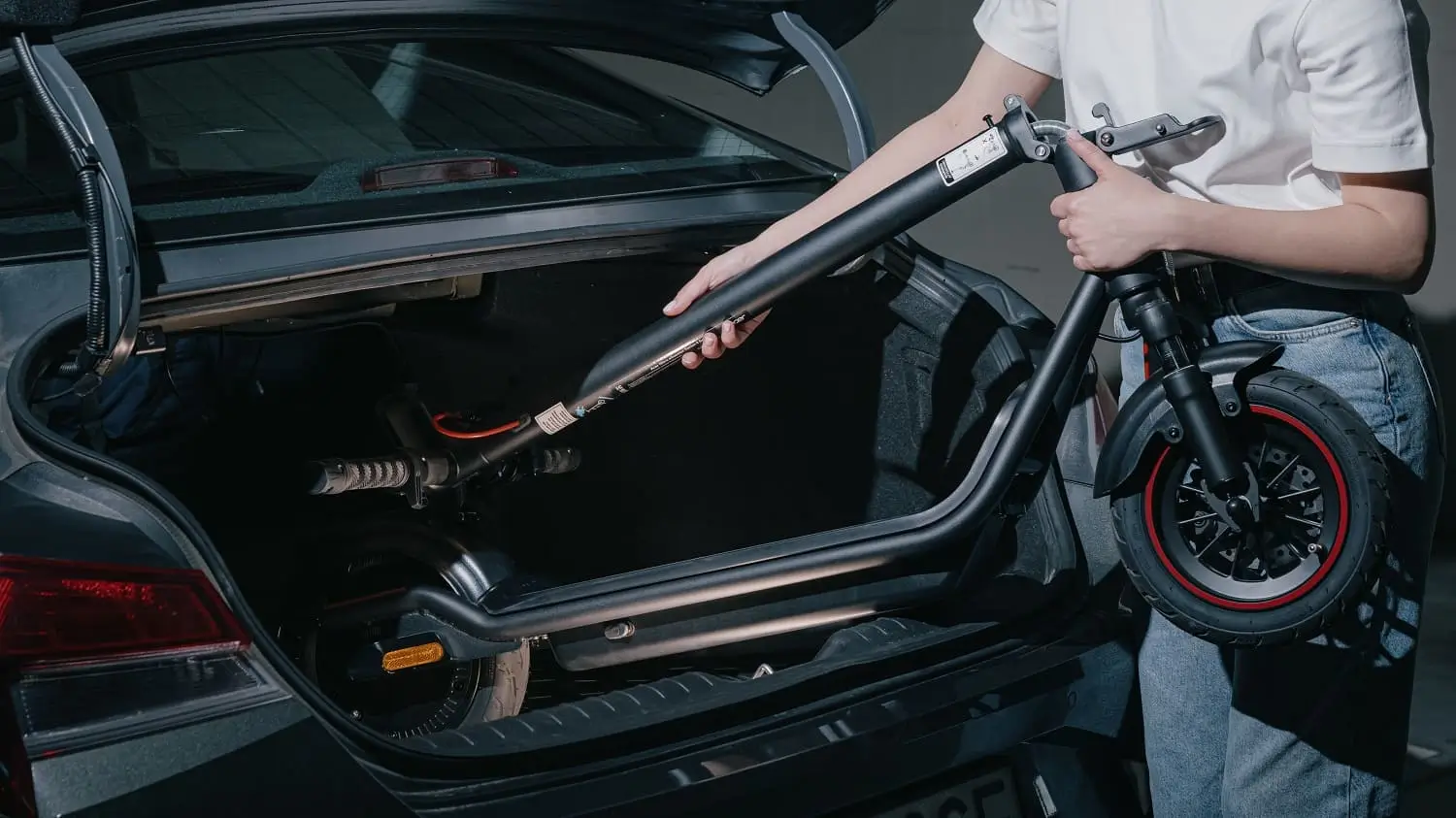 Людина кладе складений скутер у багажник