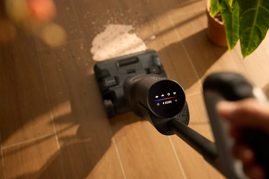 Пилосос видаляє пляму від молока з дерев'яної підлоги.