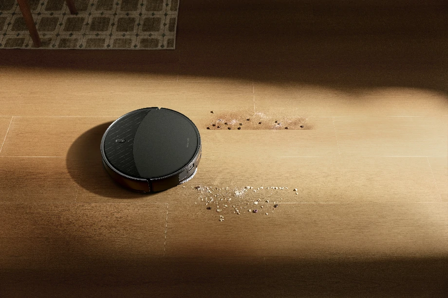 Чорний пристрій ефективно пилососить крихти їжі, розкидані по підлозі.