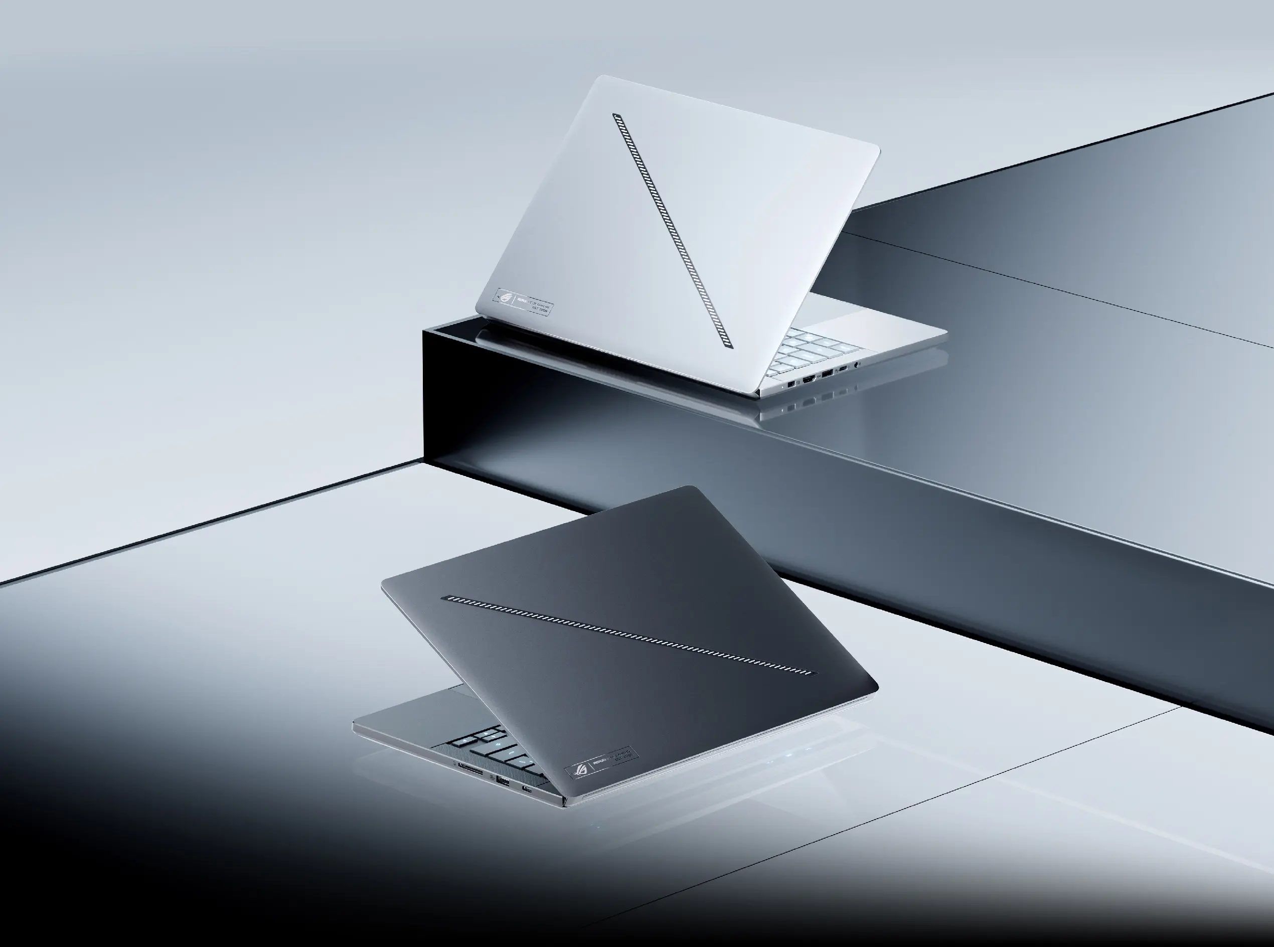 Zephyrus G16 кольорів Eclipse Grey та Platinum White на сірому фоні – обидва з відкритою верхньою кришкою.