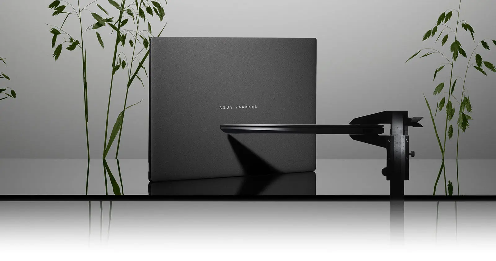 Zenbook S16 зображено на темному фоні. На передньому плані знаходиться штангенциркуль, який вимірює його товщину.