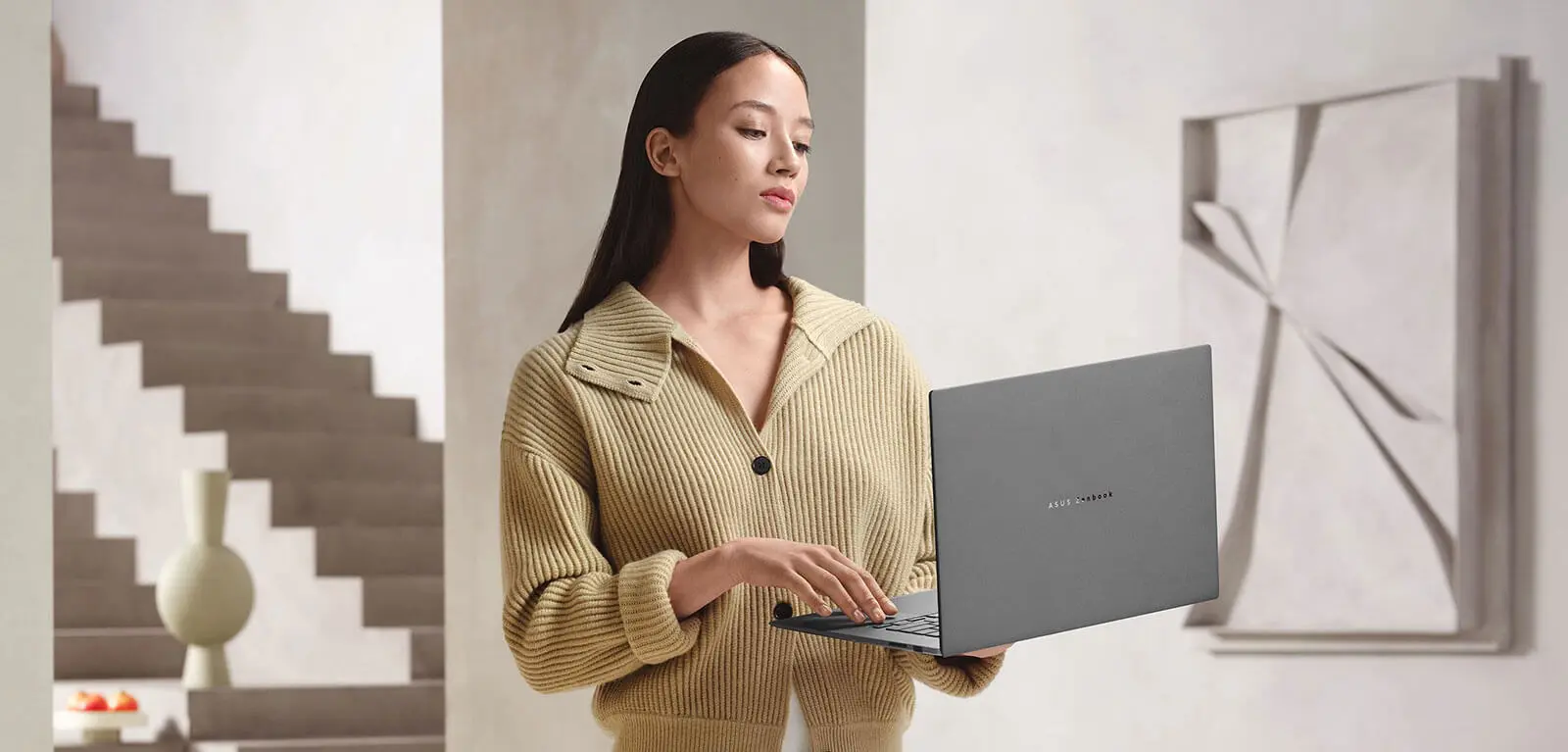 Жінка тримає Zenbook S16 однією рукою, що підкреслює його легкість та мобільність.