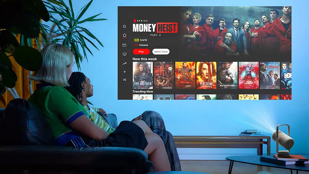 Двоє людей зручно розташовуються на дивані у вітальні, поруч стоїть XGIMI Vibe One, який проектує зображення на стіну