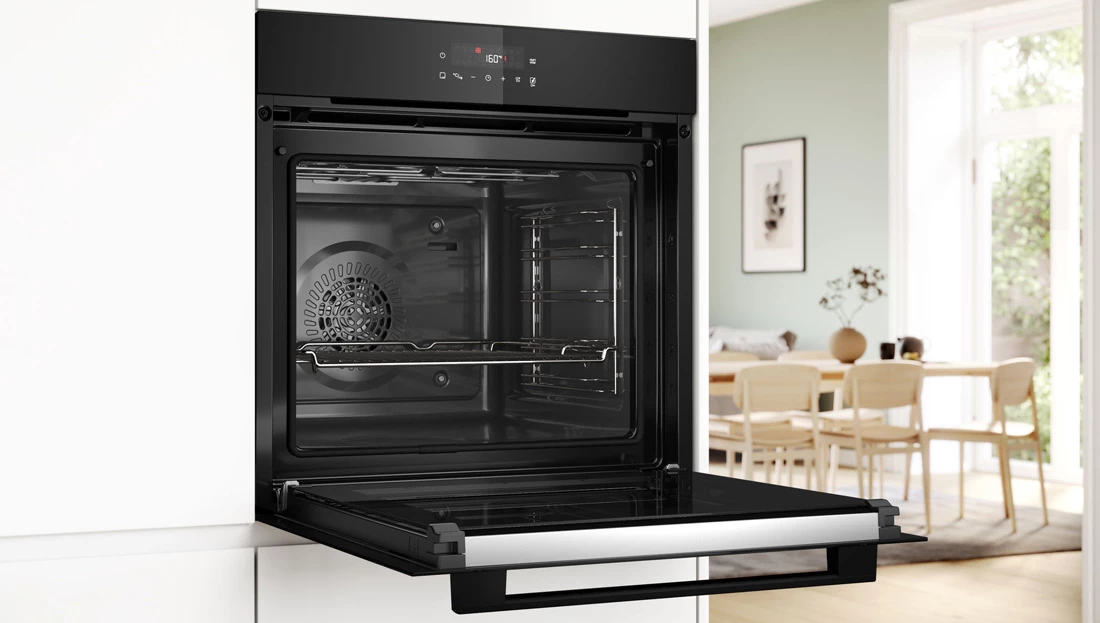 Відкрита духовка, вбудована в сучасну кухню з видимим внутрішнім простором та злегка прочиненими дверцятами