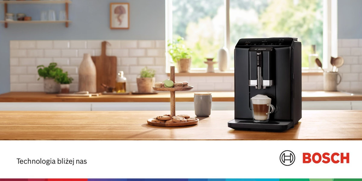 На кухонній стільниці стоїть кавоварка з приготованою кавою. Ліворуч — тарілка з печивом.