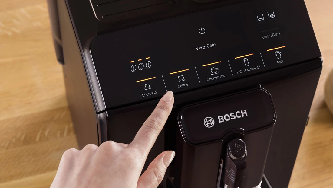Кавомашина з видимим дисплеєм. Дамський палець вказує на вибір кави.