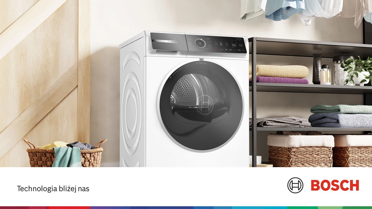 Сушарка для білизни розташована біля стіни. Ліворуч стоїть плетений кошик з одягом, а праворуч — полиця з рушниками.