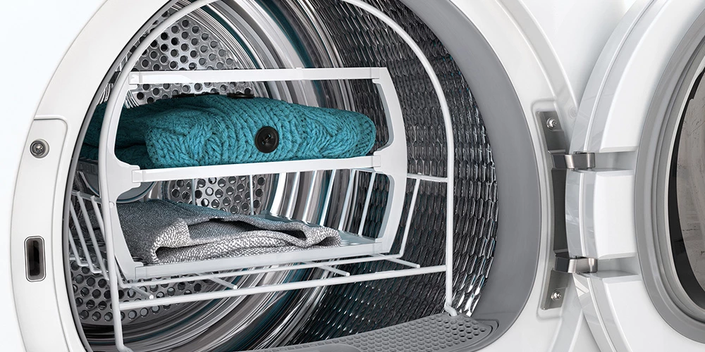 Внутрішня частина сушарки Bosch з полицею, на якій лежать светр і тканина.