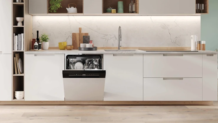 Біла посудомийна машина з прочиненими дверцятами на кухні, всередині видно посуд.