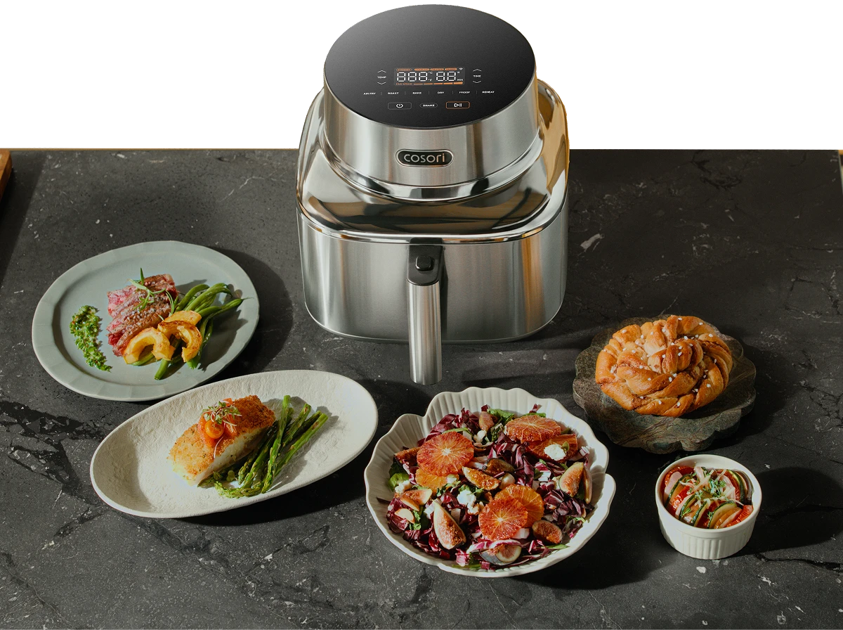 Фритюрниця Cosori, оточена готовими стравами: м'ясо з овочами, салат та випічка