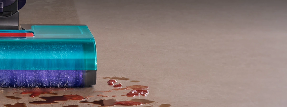 Крупний план правої сторони щітки швабри під час роботи. Валик збирає бруд, крихти та змиває плями з підлоги.