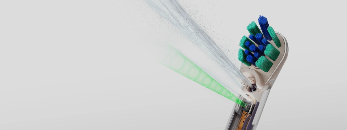 Крупний план щітки-насадки Dyson CameraJet, насадки-іригатора, з якої виходить вода, та камери під насадкою.