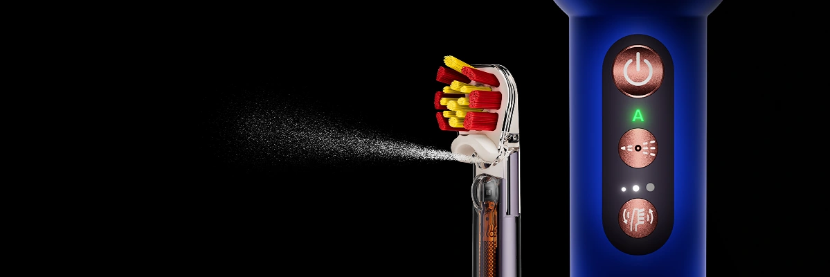 Насадка-щітка Dyson Sensitive з червоною та жовтою щетиною та водяною насадкою. Далі крупним планом корпус щітки Dyson та кнопок.