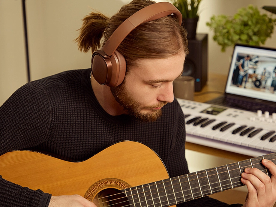 Чоловік у навушниках грає на гітарі