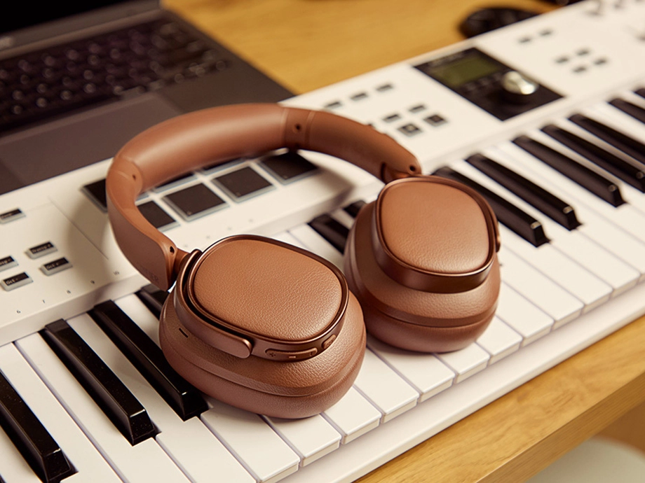 Рудоволоса жінка з чашкою кави слухає музику в коричневих навушниках-накладках