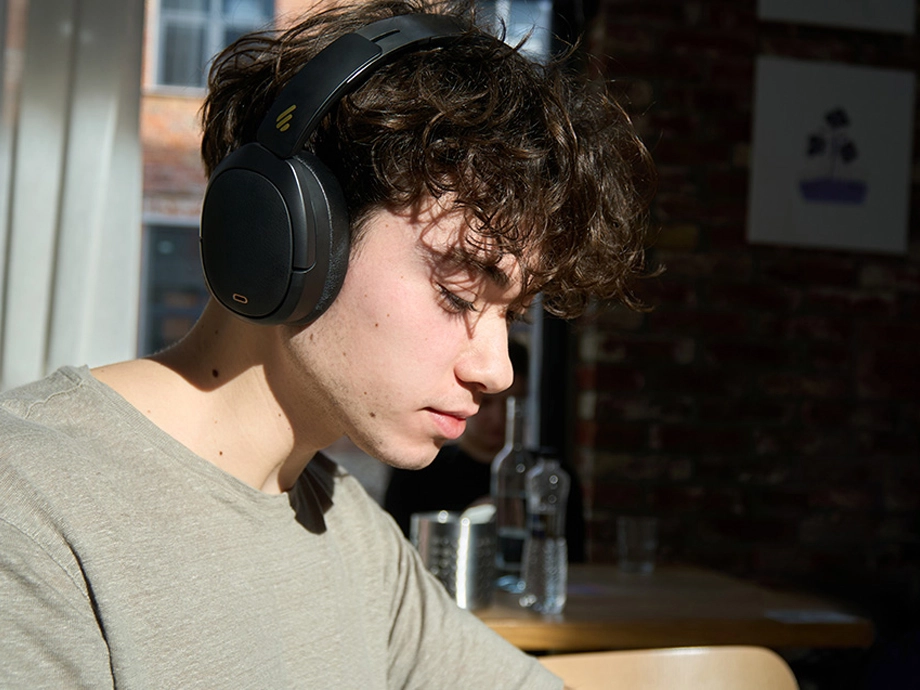 Кучерявий хлопець у темних навушниках дивиться вниз на кафе