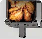 Вид зверху вниз на кошик фритюрниці Ninja, розгорнутий та наповнений золотистою смаженою куркою.