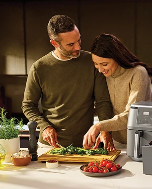 Щаслива пара нарізає овочі на вечерю, а поруч на столі стоїть фритюрниця Ninja.