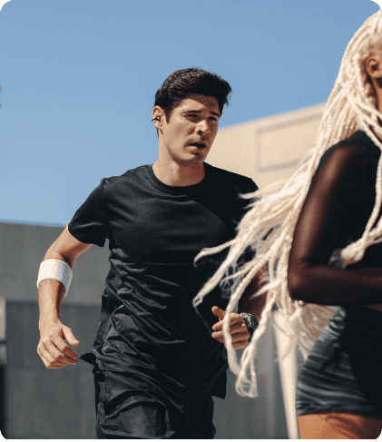 Біжать троє молодих людей у ​​спортивному одязі. Темноволосий чоловік у навушниках Huawei FreeClip 2.