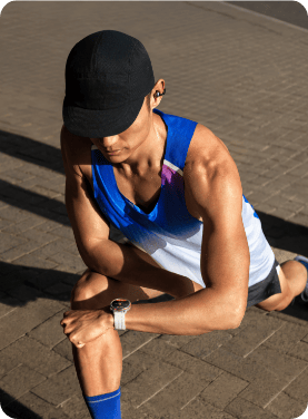 Скульптурний чоловік дивиться на своє зап'ястя під час потягування, одягнувши годинник HUAWEI Watch GT Runner 2.