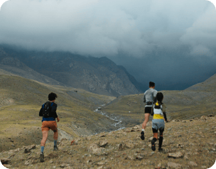 Група бігунів на крос-кантрі біжить гірським, кам'янистим та гравійним ландшафтом.