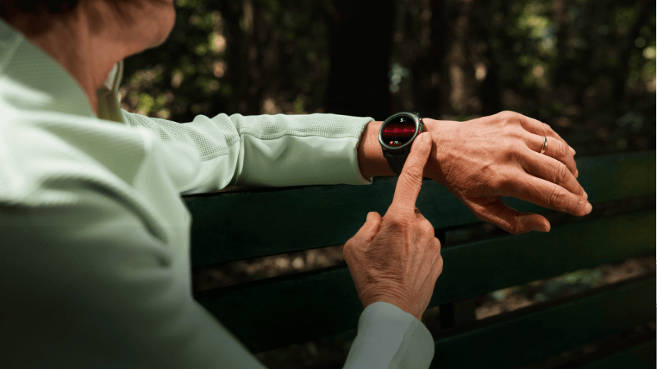 Екран годинника HUAWEI Watch GT Runner 2 на зап'ясті чоловіка у спортивній толстовці відображає червоний лінійний графік та значок серця.