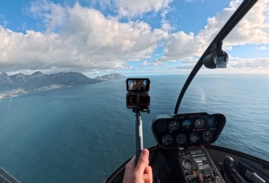 Osoba siedzi w helikopterze i używa Insta360 Ace Pro 2, aby uchwycić rozległy widok oceanu.