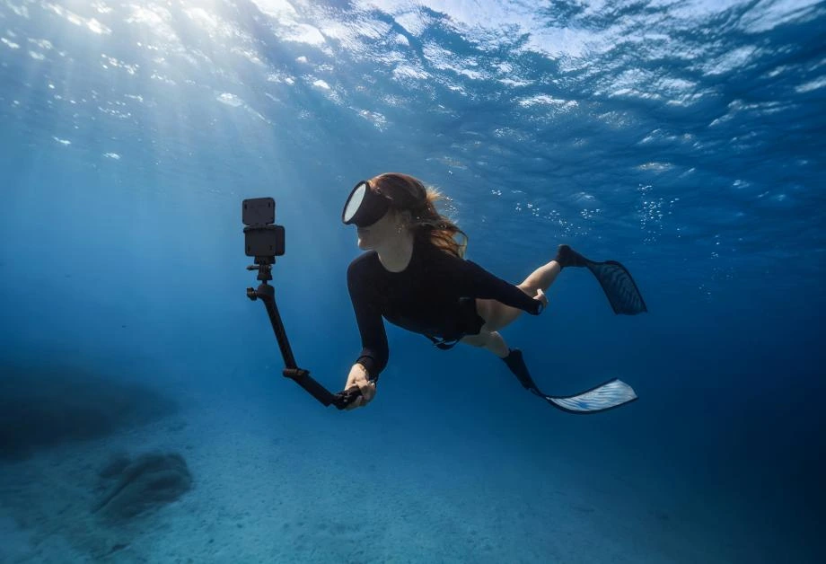 Dziewczyna korzysta z Insta360 Ace Pro 2 z kijem do selfie pod wodą, aby uchwycić krajobraz dna morskiego.