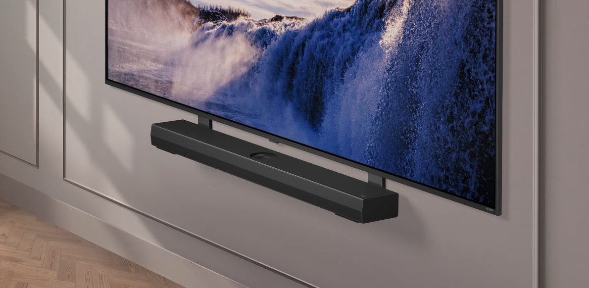 Uchwyt Synergy pokazano z LG QNED TV. Uchwyt Synergy i odbiornik LG QNED TV są przymocowane razem, a obraz przesuwa się w dół, prezentując dolną część telewizora. LG Soundbar pojawia się, gdy jest umieszczony na uchwycie Synergy. Tło pojawia się razem ze ścianą.