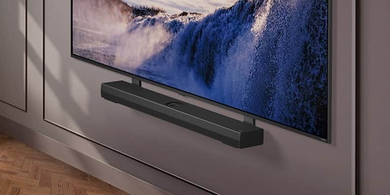 Uchwyt Synergy pokazano z LG QNED TV. Uchwyt Synergy i odbiornik LG QNED TV są przymocowane razem, a obraz przesuwa się w dół, prezentując dolną część telewizora. LG Soundbar pojawia się, gdy jest umieszczony na uchwycie Synergy. Tło pojawia się razem ze ścianą.
