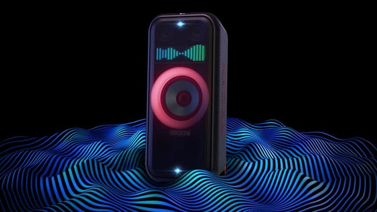LG XBOOM XL7S stoi w nieograniczonej przestrzeni. Czerwone oświetlenie głośnika niskotonowego i podwójne oświetlenie stroboskopowe są włączone. Na górze głośnika wyświetlany jest poziom głośności. Fale dźwiękowe wydobywają się spod głośnika w celu podkreślenia jego głębokiego basu.