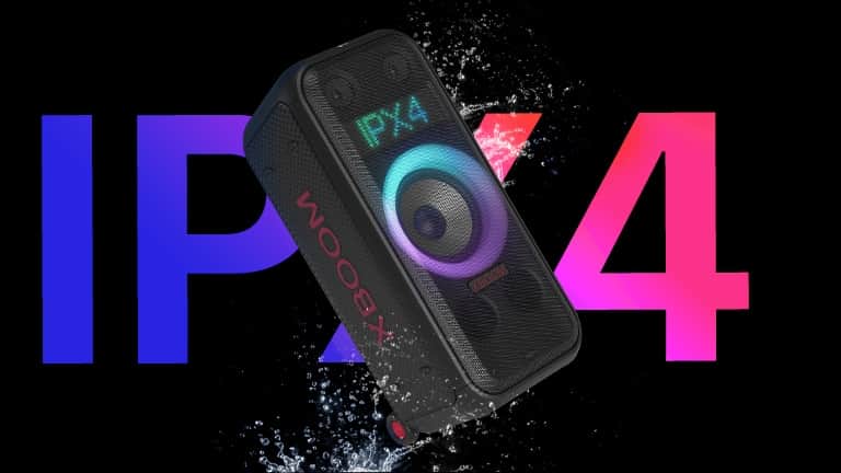Widok głośnika pod kątem. Produkt jest spryskiwany wodą, aby podkreślić stopień ochrony IPX4. Słowo „IPX4” jest napisane z tyłu ze względów projektowych.