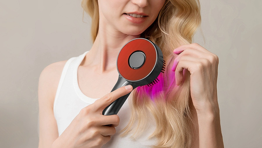Жінка використовує ВІДНОВЛЮЮЧУ МАСАЖЕР-ЩІТКУ ДЛЯ ВОЛОССЯ MT6537 з функцією світлотерапії – вид спереду.