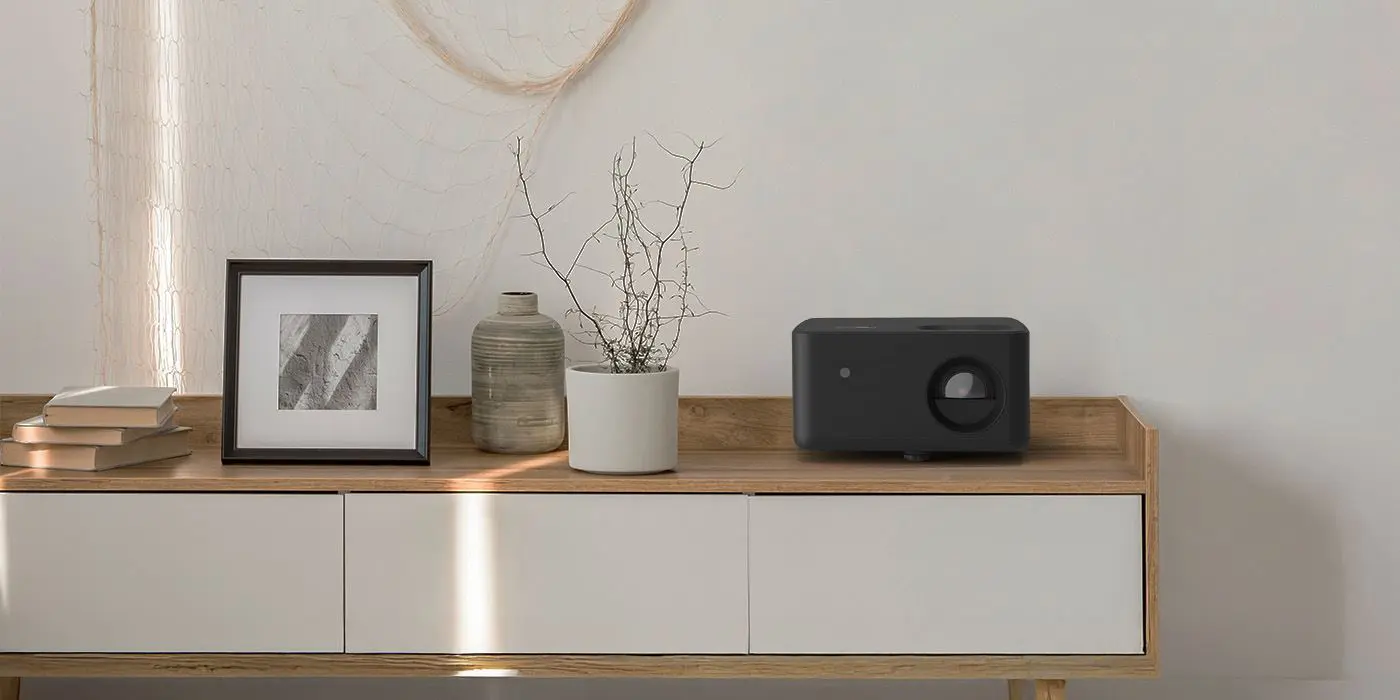 Проектор Optoma PK32, розміщений на комоді в сучасному інтер'єрі.