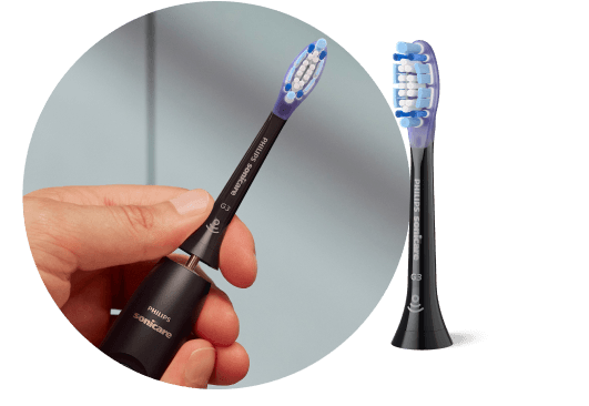 Рука тримає зубну щітку без наконечника. Кінчик щітки поруч.