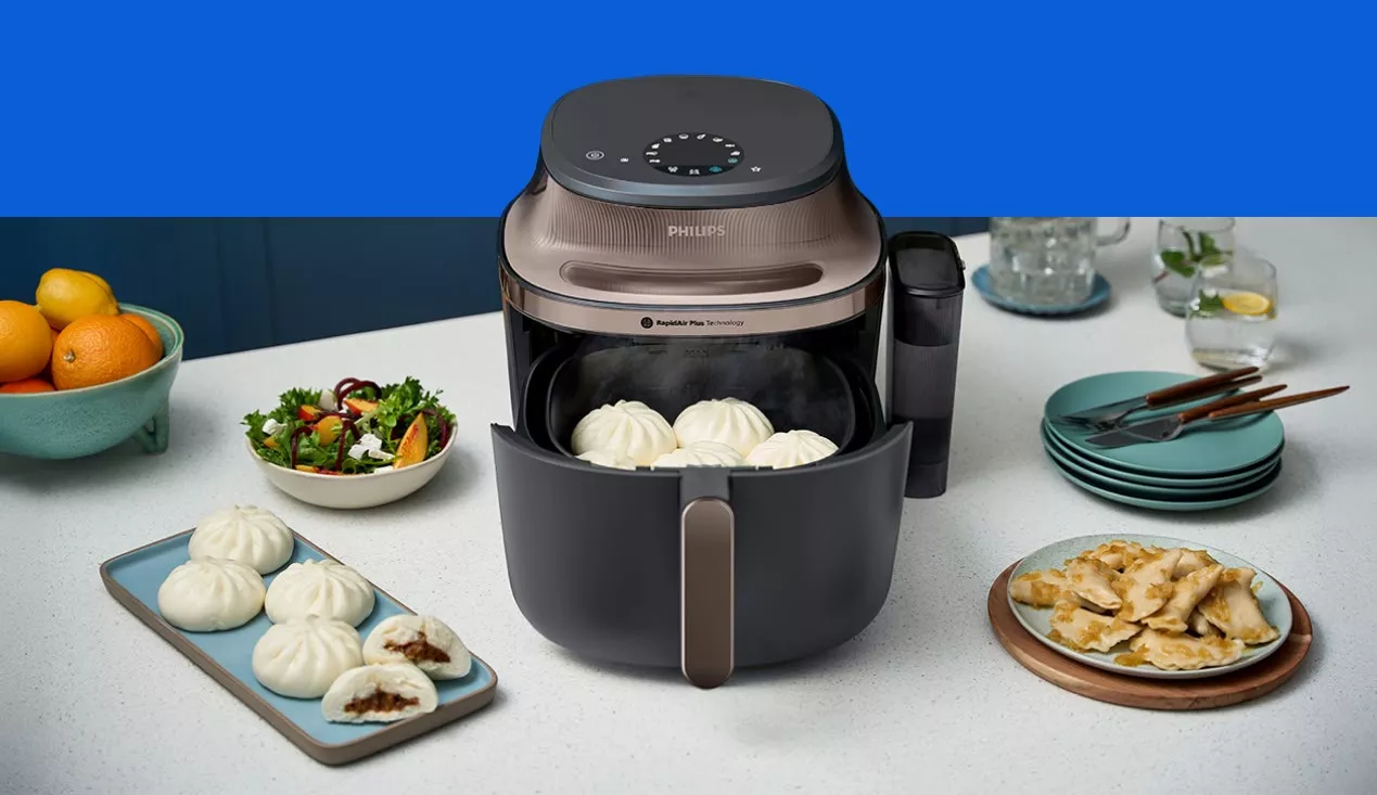 Аерофритюрниця Philips NA547/07 розміщена на кухонному острові, а навколо неї вже приготовані страви.