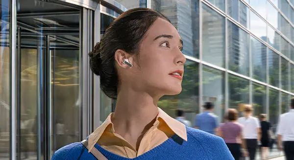 Жінка з білими навушниками Galaxy Buds4 Pro у вусі дивиться праворуч.