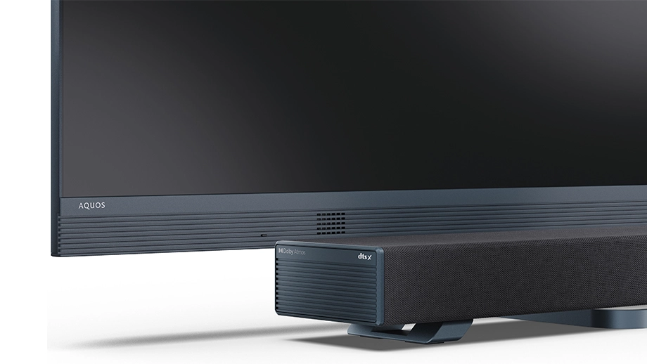 Крупний план саундбара, що стоїть поруч із телевізором Sharp із центральною підставкою.