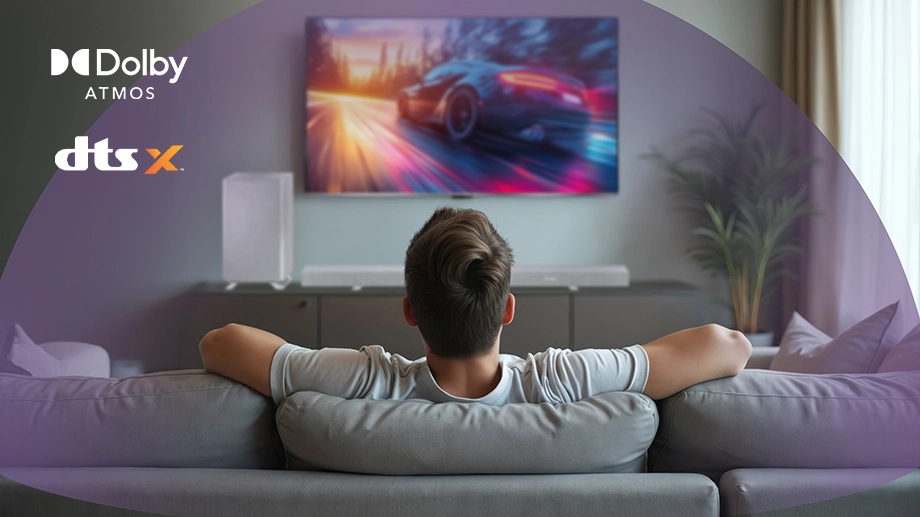 Чоловік сидить перед телевізором із саундбаром та сабвуфером; звукові хвилі; логотипи Dolby Atmos та DTS:X (Digital Theatre Systems:X)