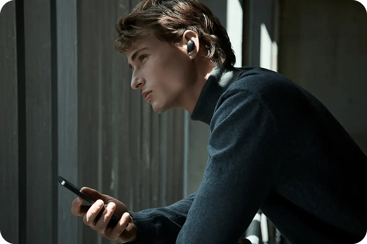 Чоловік зі смартфоном у чорних навушниках Sony WF-1000XM6