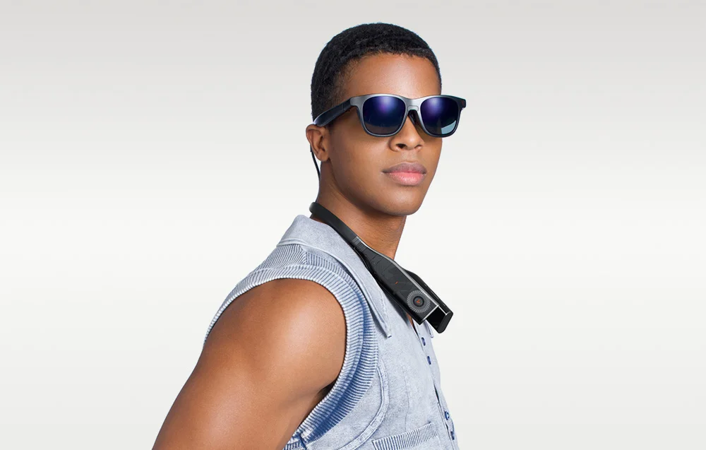 Чоловік у синьому жилеті дивиться вперед, в окулярах XR та з пов'язкою на шиї.