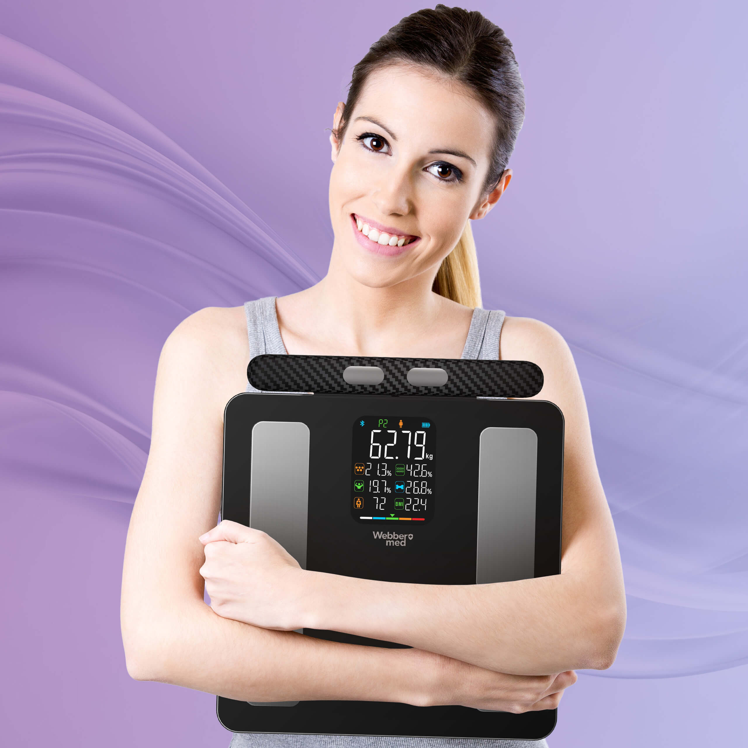 Усміхнена жінка тримає медичні розумні ваги Webber з кольоровим світлодіодним дисплеєм та вимірювальними електродами.