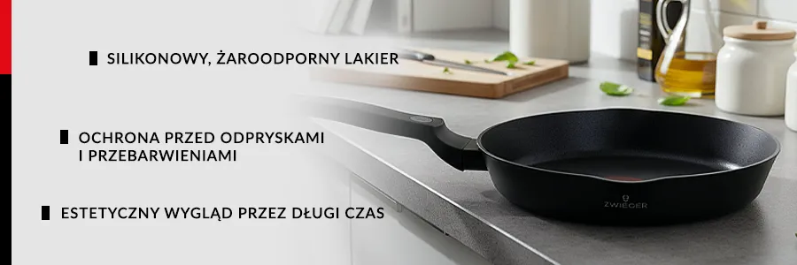 Patelnia ZWIEGER KORRA położona na ciemnym blacie kuchennym, na drugim planie deska do krojenia z nożem oraz dzbanek z oliwą