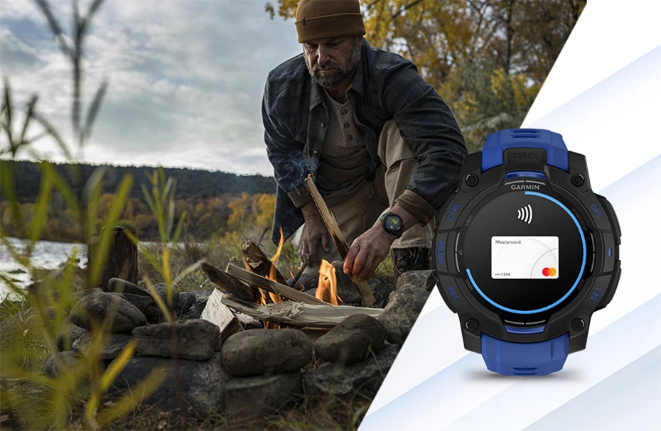 Мужчина разводит костер у реки, рядом с ним лежат часы Garmin Instinct 3 с экраном бесконтактной оплаты Garmin Pay.